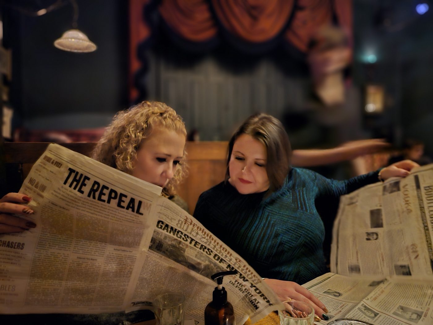 Reading newspaper cocktail menus in a prohibition-themed bar, Chester