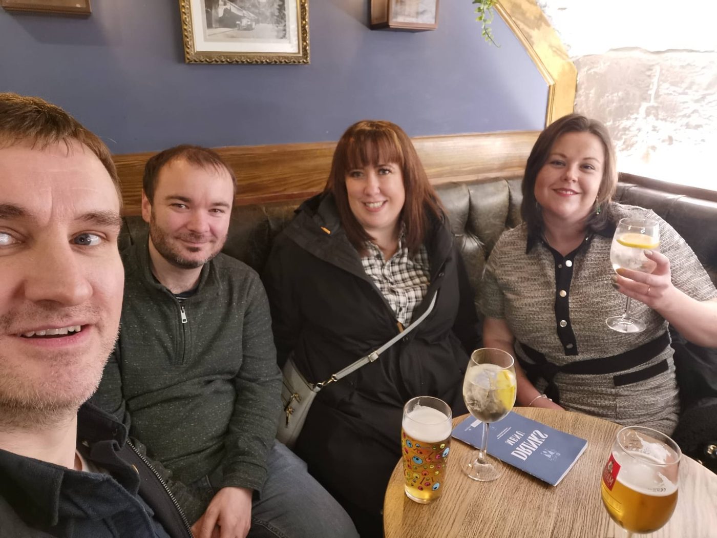 The four of us in a pub booth with the drinks menu on the table, Manchester December 2022